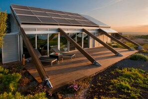 A modern house with a sloped roof, large windows, and a wooden deck. - Casas Bioclimáticas Iter El Muro (Granadilla de Abona)