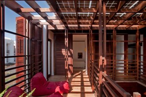 A corridor with wooden slats and a red bean bag chair. - Casas Bioclimáticas Iter El Cubo (Granadilla de Abona)