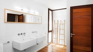 A bathroom with two sinks, a mirror, and a wooden door. - Casas Bioclimáticas Iter El Cubo (Granadilla de Abona)