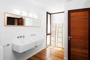 A bathroom with two sinks, a mirror, and a wooden door. - Casas Bioclimáticas Iter El Cubo (Granadilla de Abona)