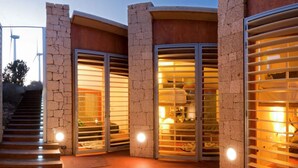 A modern building with stone walls and large glass doors leading to interior spaces. - Casas Bioclimáticas Iter La Estrella (Granadilla de Abona)