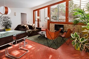 A living room with a sofa, chairs, a TV, and a dining area with a table and chairs. - Casas Bioclimáticas Iter La Estrella (Granadilla de Abona)