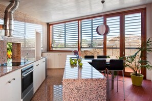 A modern kitchen with granite countertops, a built-in oven, and a large island with seating. - Casas Bioclimáticas Iter La Estrella (Granadilla de Abona)
