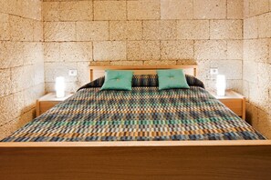 Una habitación con una cama, dos mesitas de noche y una colcha estampada.