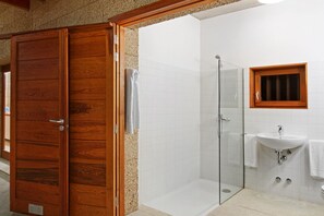 A bathroom with a wooden door, a glass shower enclosure, and a white sink. - Casas Bioclimáticas Iter La Tea (Granadilla de Abona)