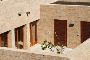 A building with a stone facade, wooden shutters, and a small plant in the foreground. - Casas Bioclimáticas Iter La Tea (Granadilla de Abona)