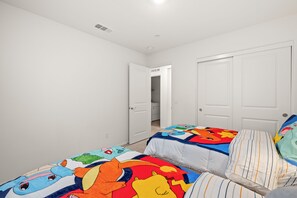 Une chambre avec deux lits, des murs blancs et une porte qui donne sur une autre pièce.