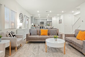 Una sala de estar moderna con un conjunto de sofá, una mesa de centro y una zona de comedor con una cocina al fondo.