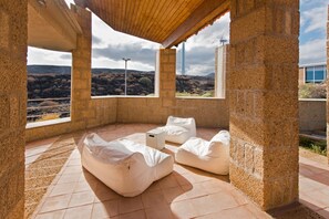Un espace extérieur abrité, doté de murs en pierre et de grandes fenêtres donnant sur un paysage vallonné.