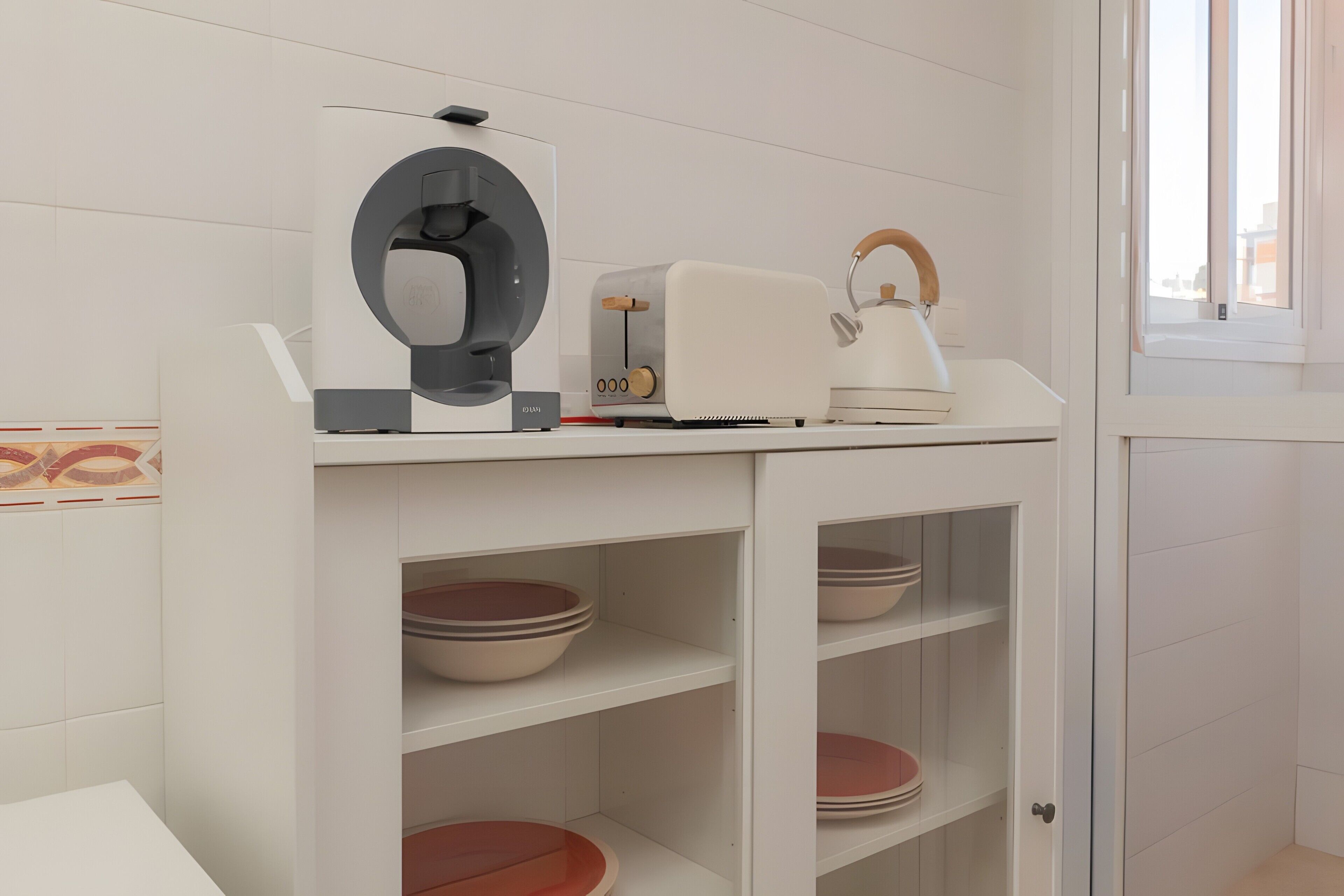 A kitchen with white cabinets, a kettle, a toaster, and a coffee machine.