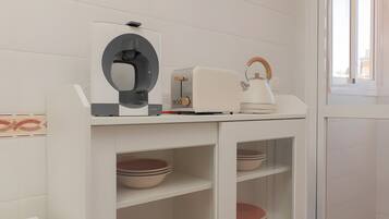 A kitchen with white cabinets, a kettle, a toaster, and a coffee machine.