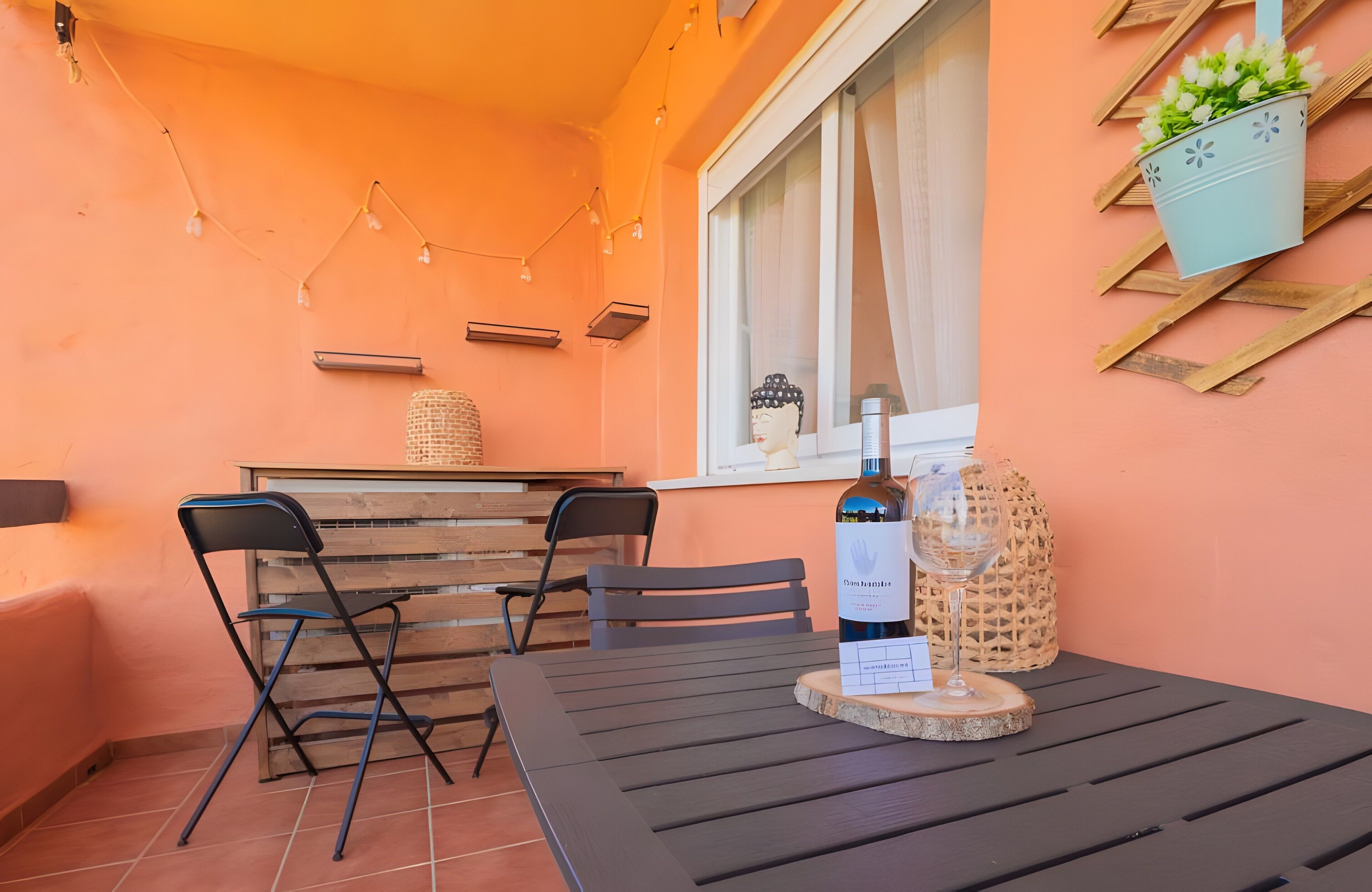 Un patio con una mesa, sillas, una botella de vino y una copa.
