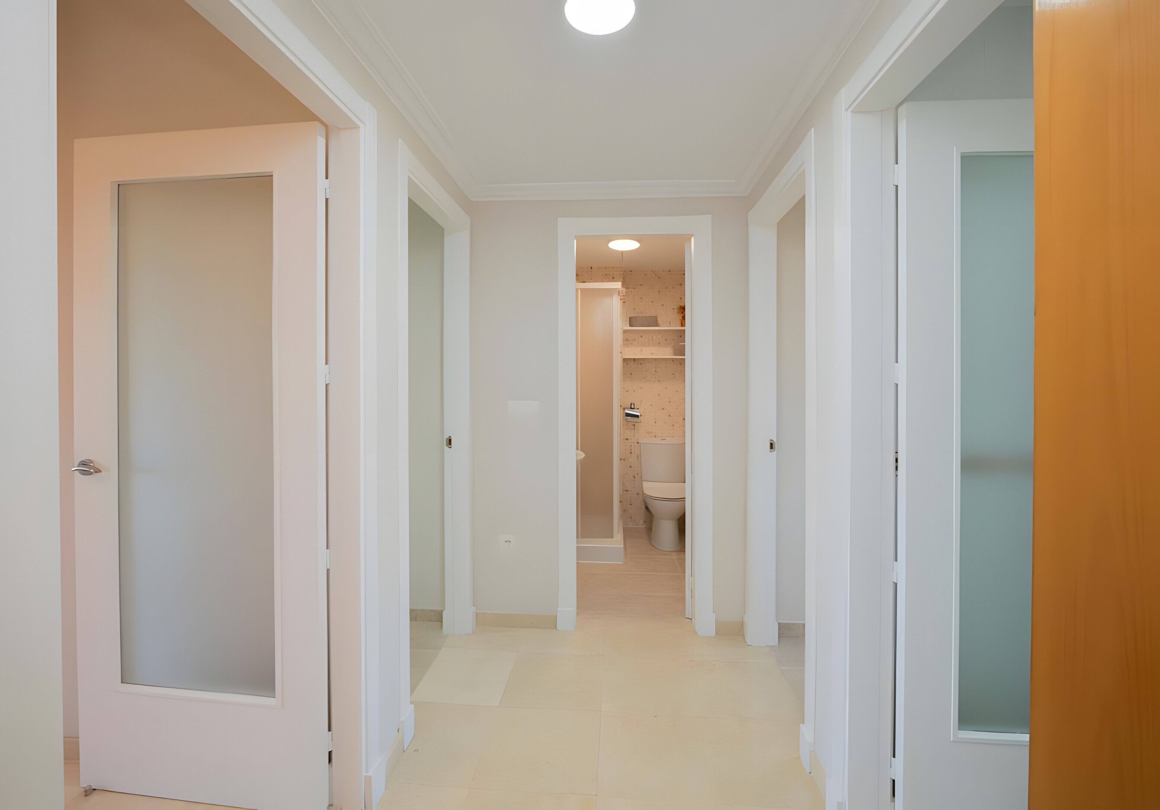 Ein Flur, der zu einem Badezimmer mit Toilette und Ablagefläche führt.