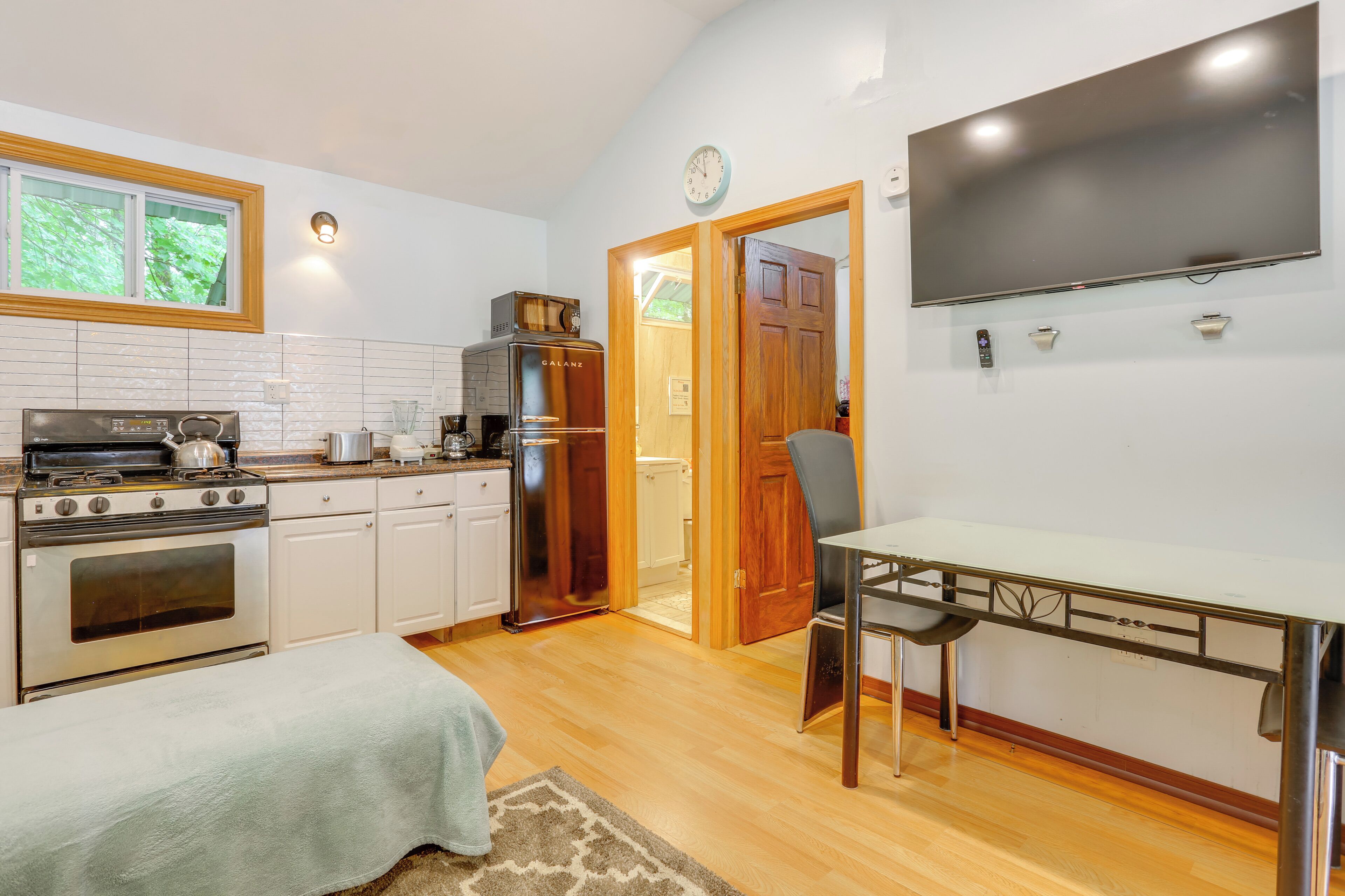 A modern kitchen with stainless steel appliances, a dining table, and a flat-screen TV.