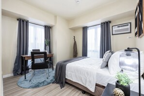 A bedroom with a bed, a desk, a chair, and a window with curtains. - Fully Furnished 2-Bedroom Condo in Cebu IT Park Near Sugbo Mercado & Ayala Mall (Cebu City)