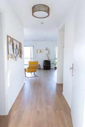 A spacious hallway with wooden flooring, a yellow rocking chair, and a large black barrel. - Apartment 'Ferienwohnung Zweitblick Koblenz' with Balcony and Wi-Fi (Koblenz)