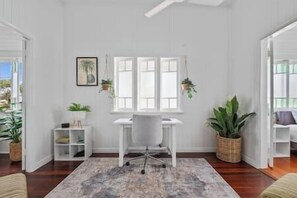 Ein Zimmer mit Schreibtisch, Stuhl und Topfpflanzen.