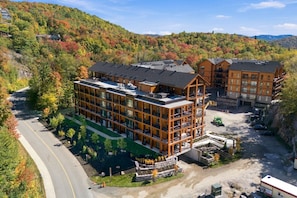A multi-story hotel with a modern design, situated in a mountainous area with autumn foliage. - Modern Mont-Tremblant Getaway -Ostrya (Mont-Tremblant)