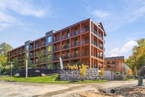 Ein mehrstöckiges Hotel mit Balkonen, einem angelegten Vorgarten und blauem Himmel.