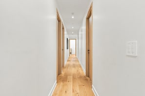 Un couloir avec des portes en bois, des murs blancs et un plancher en bois.