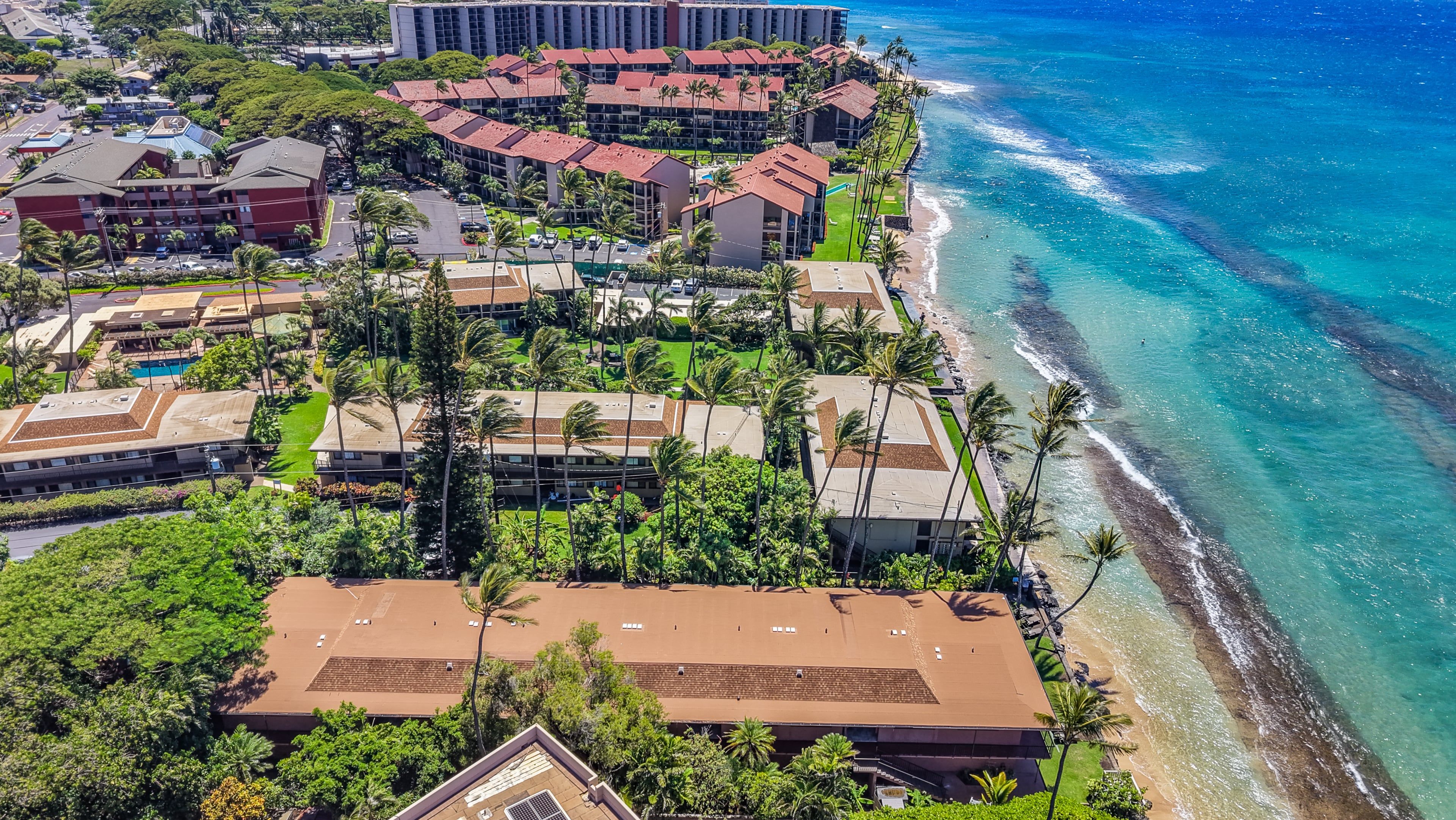 A coastal hotel with multiple buildings, a beachfront, and a clear view of the ocean.