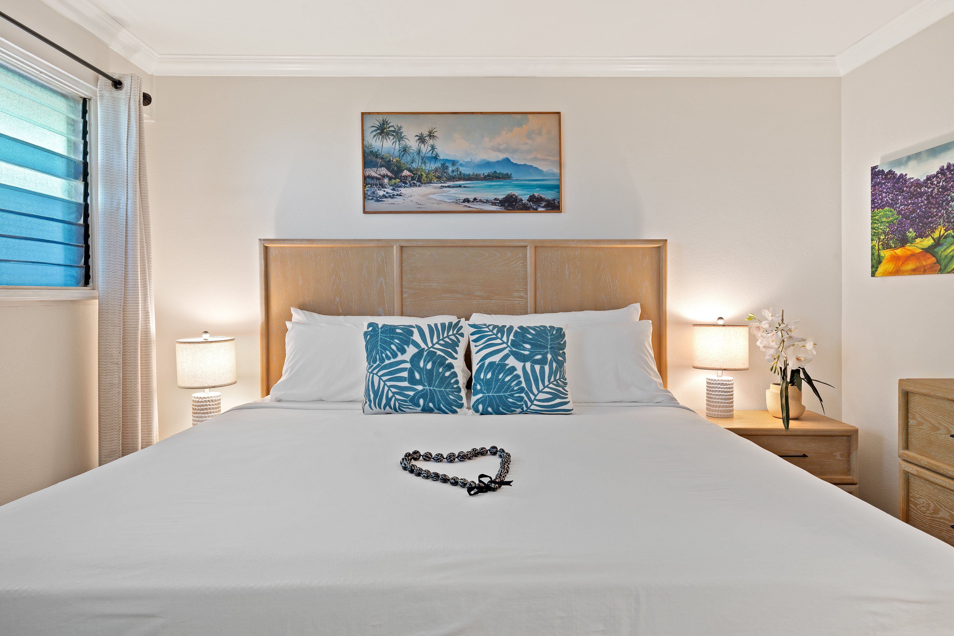 A hotel room with a bed, two nightstands, a window with blinds, and wall art.