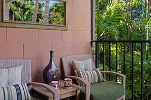 A balcony with wicker furniture, a vase, and a table with two mugs. - Garden View Condo Just Steps from the Ocean -Maui Sands Seaside 717 (Lahaina)