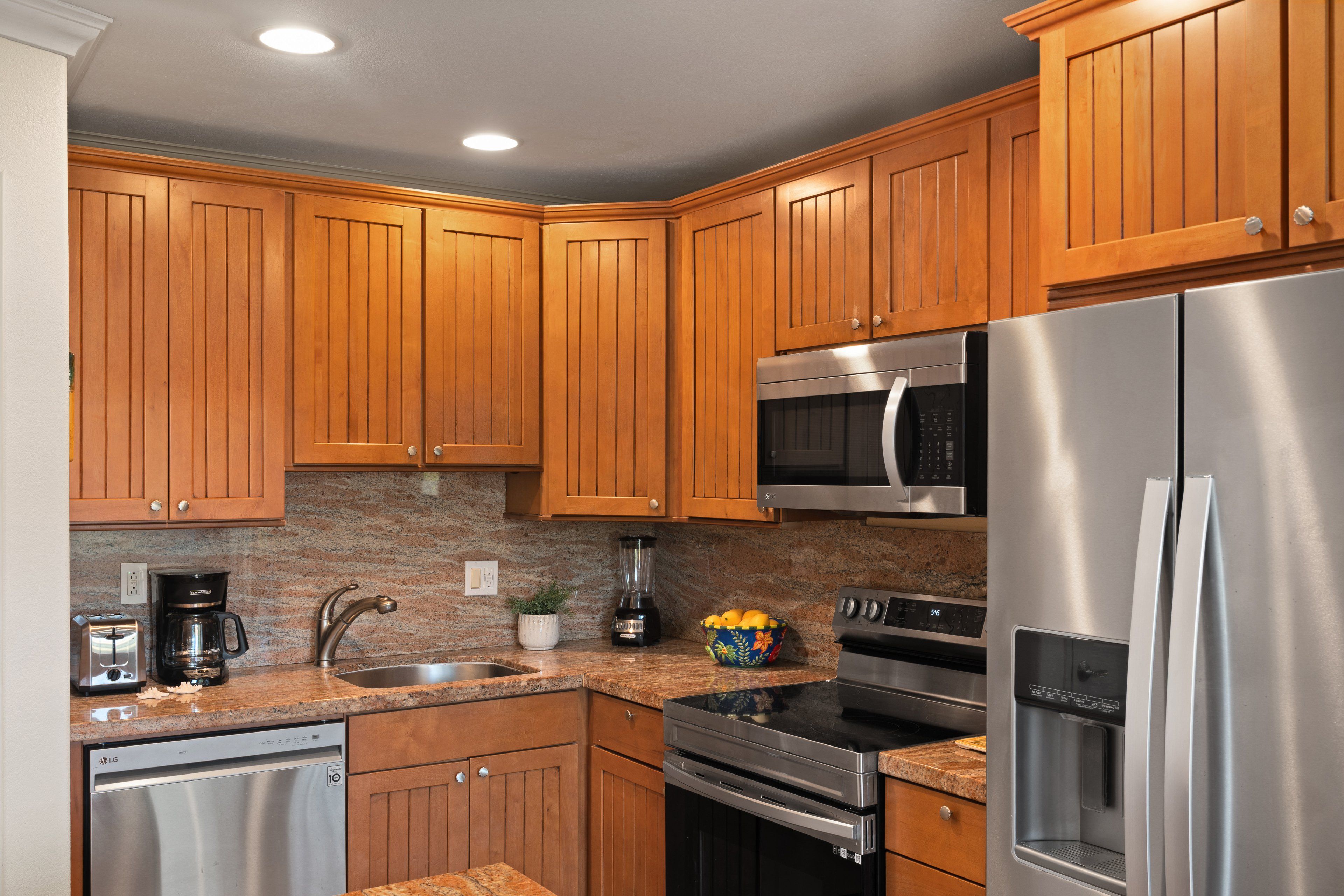 A modern kitchen with wooden cabinets, stainless steel appliances, granite countertops, and a built-in oven.