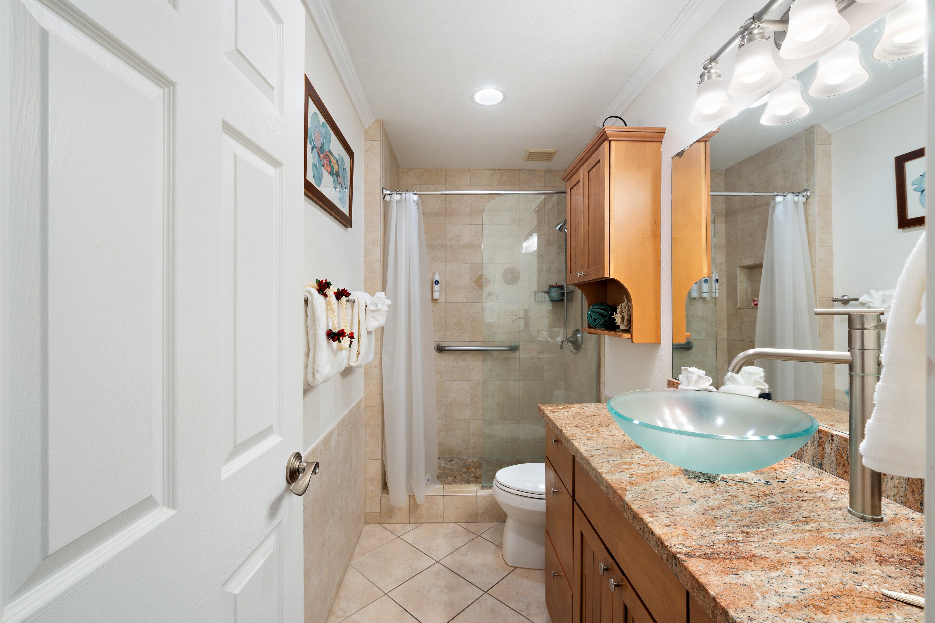 A bathroom with a glass sink, a shower, and a toilet.
