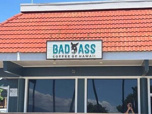 A storefront with a sign reading 'BAD ASS COFFEE OF HAWAII' and a red-tiled roof. - Garden View Condo Just Steps from the Ocean -Maui Sands Seaside 717 (Lahaina)