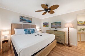 A hotel room with a bed, a nightstand, a dresser, a lamp, and a ceiling fan. - Garden View Condo Just Steps from the Ocean -Maui Sands Seaside 717 (Lahaina)