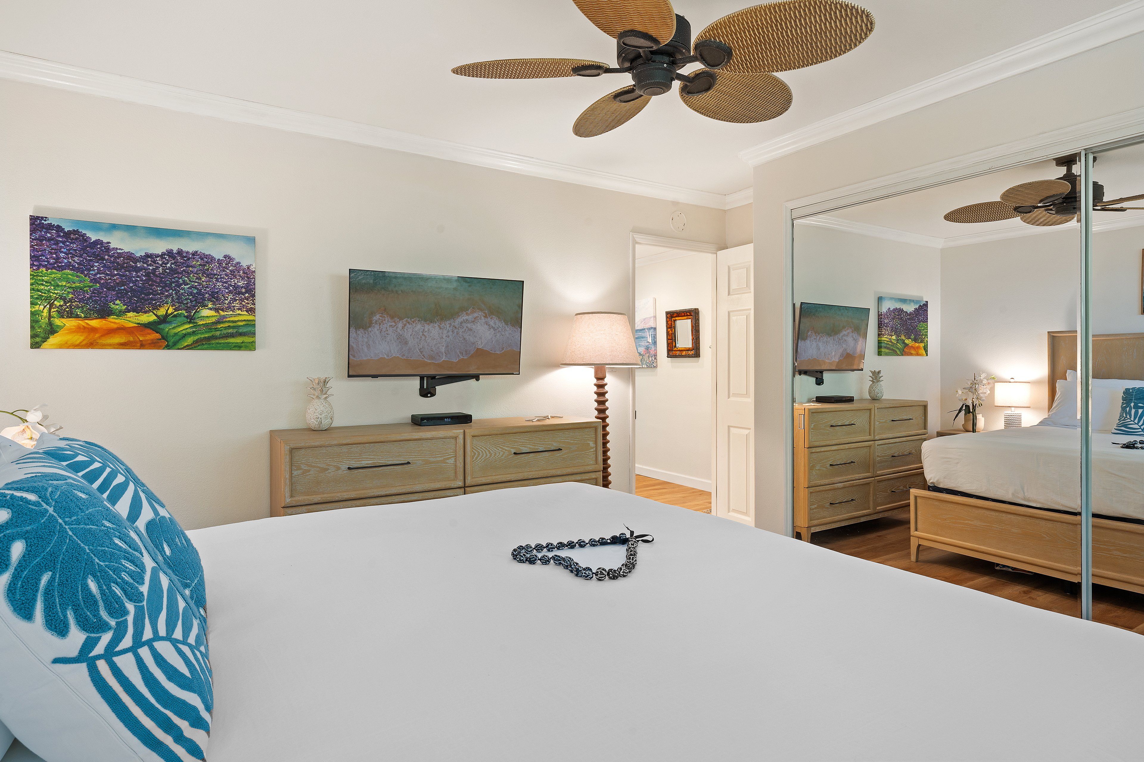 Een hotelkamer met een bed, een dressoir, een spiegel, een televisie en kunstwerken aan de muren.