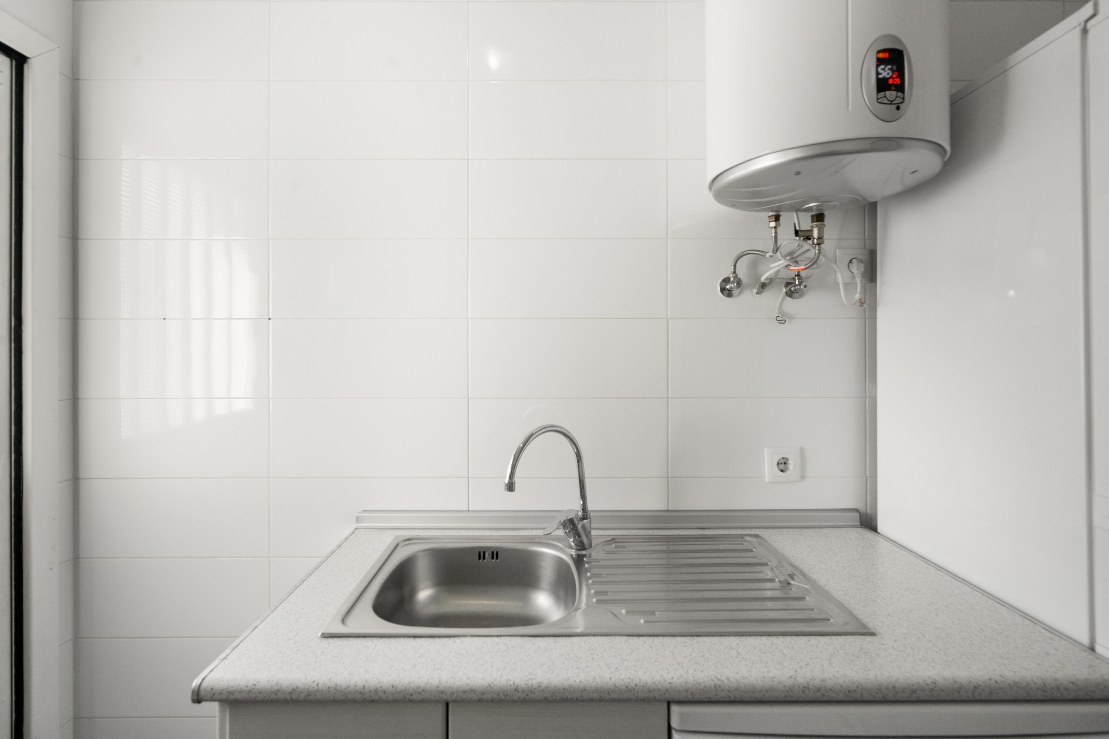 Een keuken met een RVS spoelbak, een kraan en een ingebouwde elektrische boiler.