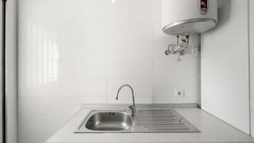 Een keuken met een RVS spoelbak, een kraan en een ingebouwde elektrische boiler.
