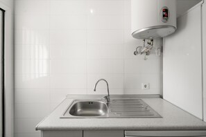 Ett kök med en diskho i rostfritt stål, en blandare och en inbyggd elektrisk varmvattenberedare.