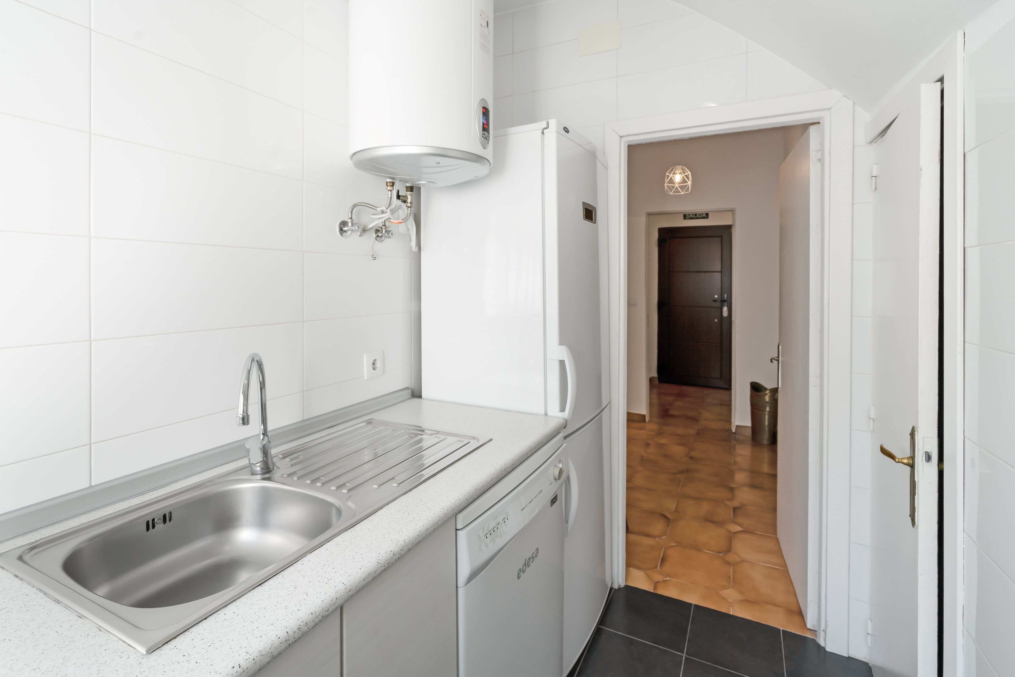 Eine moderne Küche mit einer Spüle aus Edelstahl, einem Geschirrspüler und einem weißen Kühlschrank.