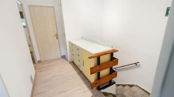 A hallway with a wooden bench, a door, and a small table with drawers.