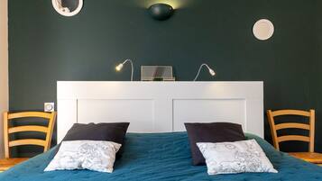 Une chambre à coucher comprenant un lit, deux chaises, un bureau et une lampe fixée au mur.