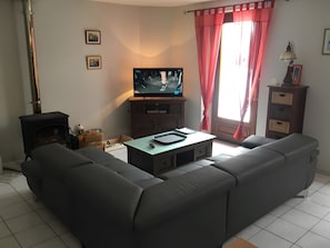 Una sala de estar con sofá, televisor, chimenea y ventana con cortinas.