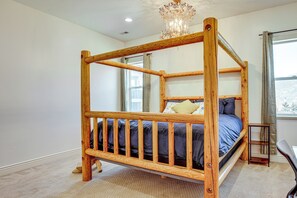 Ein hölzernes Himmelbett mit Kopfteil, ein kleiner Holzschemel und ein Fenster mit Vorhängen.