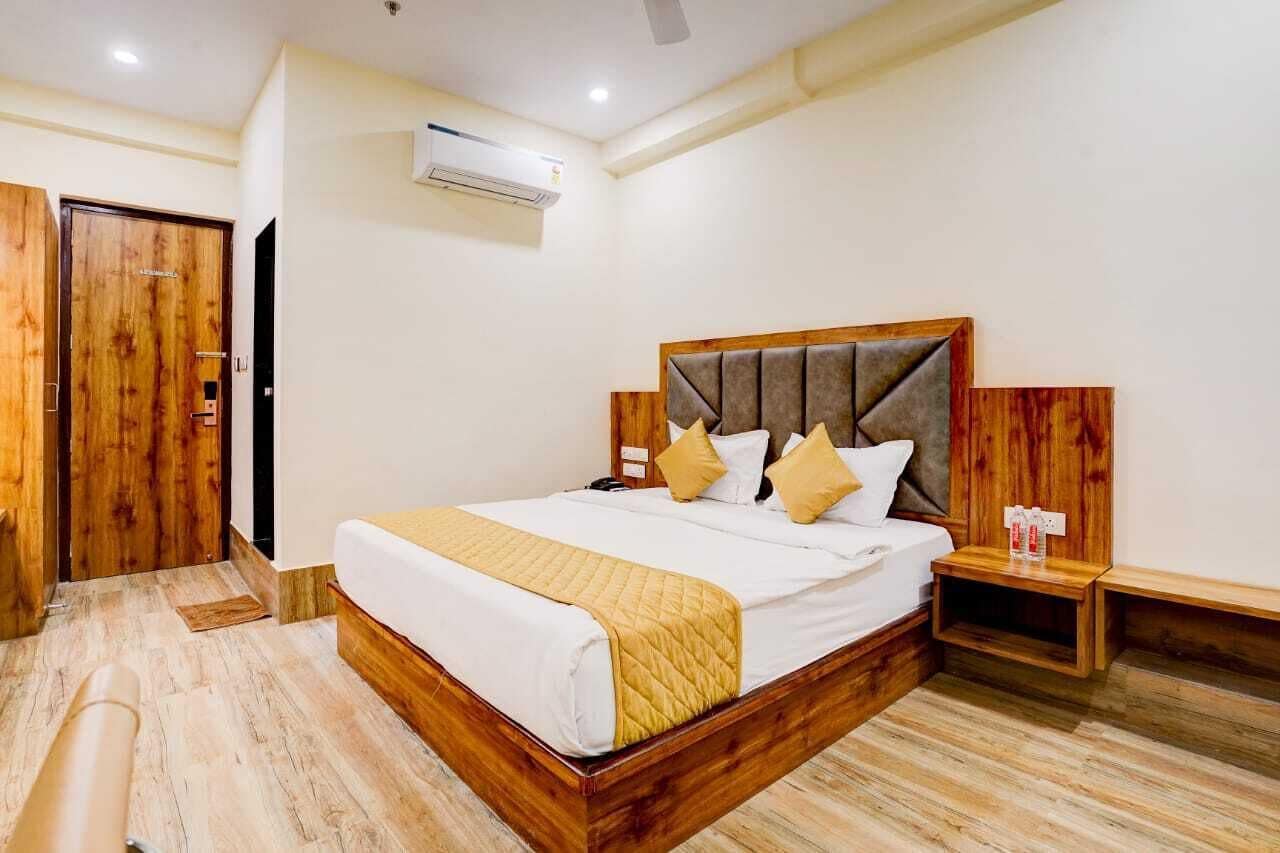 Quarto de hotel com cama de madeira, mesas de cabeceira e um guarda-roupa.