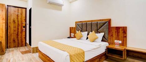 Quarto de hotel com cama de madeira, mesas de cabeceira e um guarda-roupa.