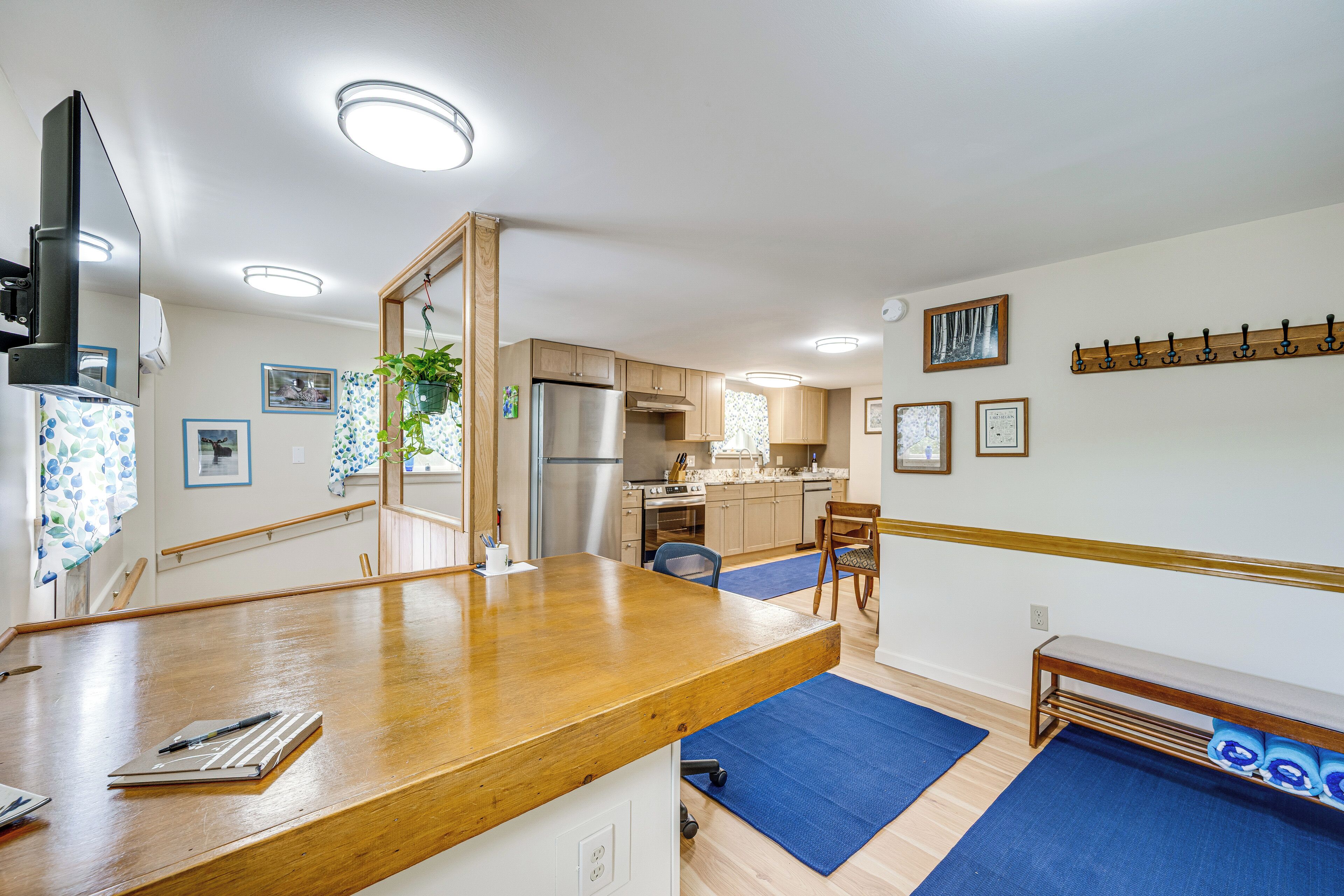 A modern kitchen with wooden cabinets, a stainless steel refrigerator, and a dining area with a wooden table and chairs.