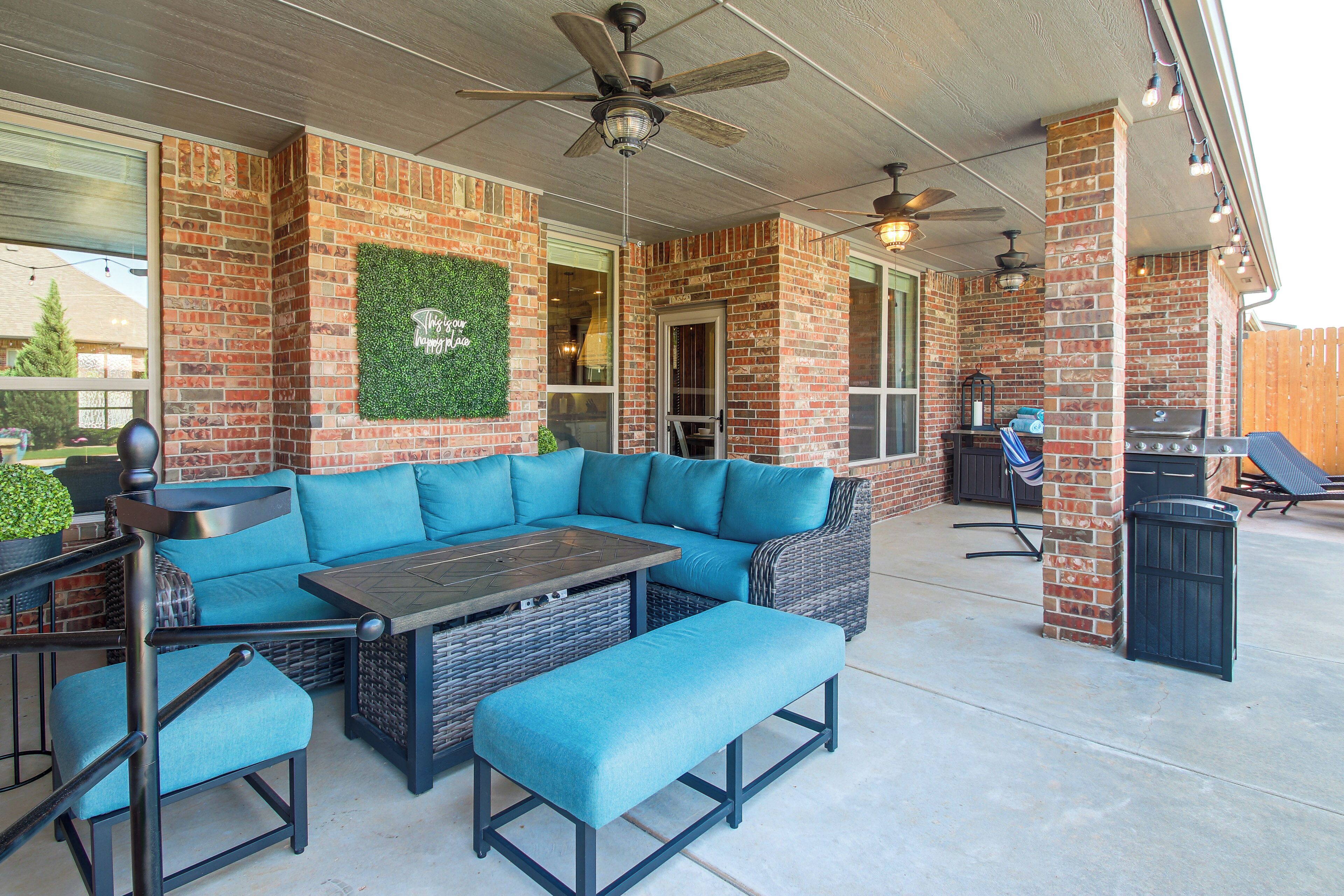 An outdoor patio with a sectional sofa, a table, and a grill area.