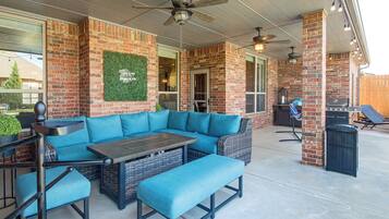 An outdoor patio with a sectional sofa, a table, and a grill area.
