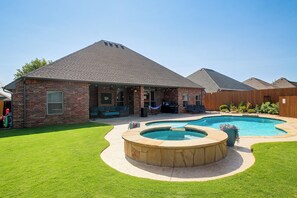 A residential property with a brick house, a swimming pool, and a landscaped yard.