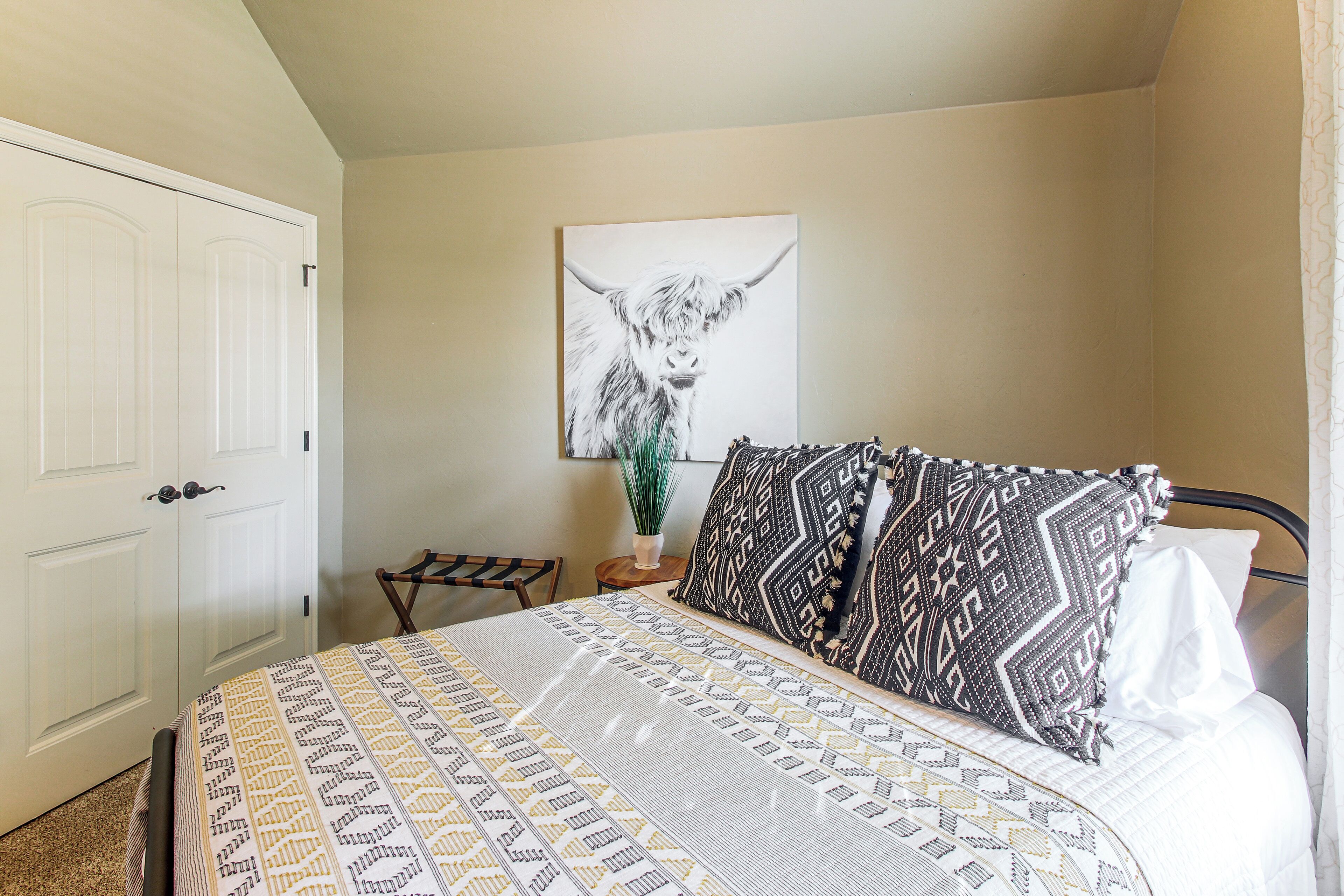 Un dormitorio con cama, una puerta, una silla y una obra de arte colgada en la pared.