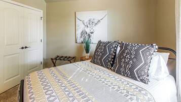 Un dormitorio con cama, una puerta, una silla y una obra de arte colgada en la pared.