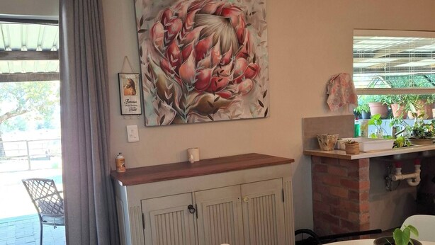 A dining area with a table, chairs, a cabinet, and a painting on the wall.