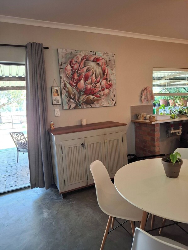 A dining area with a table, chairs, a cabinet, and a painting on the wall.